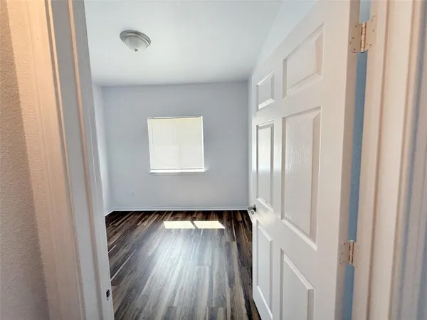 a view of a hallway with wooden floor and a bathroom
