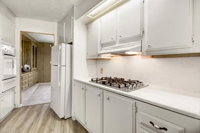 a kitchen with white cabinets and appliances
