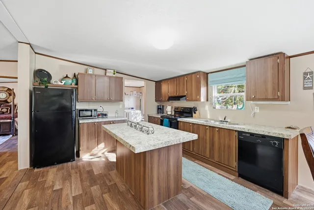 a kitchen with stainless steel appliances granite countertop a refrigerator a sink dishwasher a stove and white countertops with wooden floor