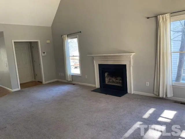 an empty room with windows and fireplace