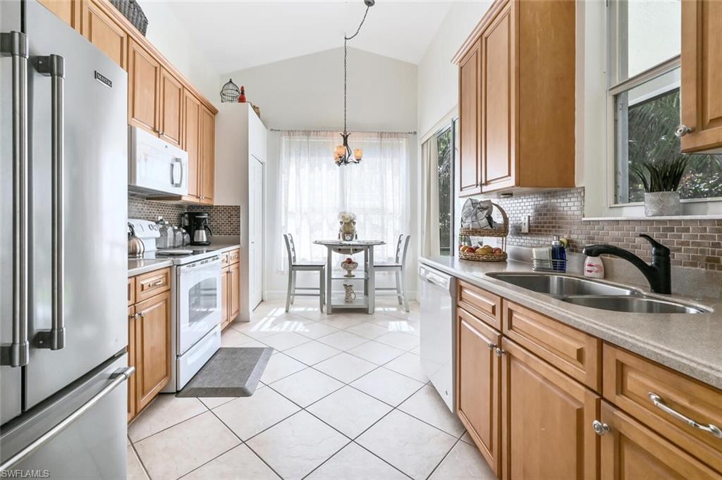 1346 Triandra Lane Naples, FL 34119 - Photo 9 of 19 a kitchen with stainless steel appliances a sink a stove a refrigerator and cabinets