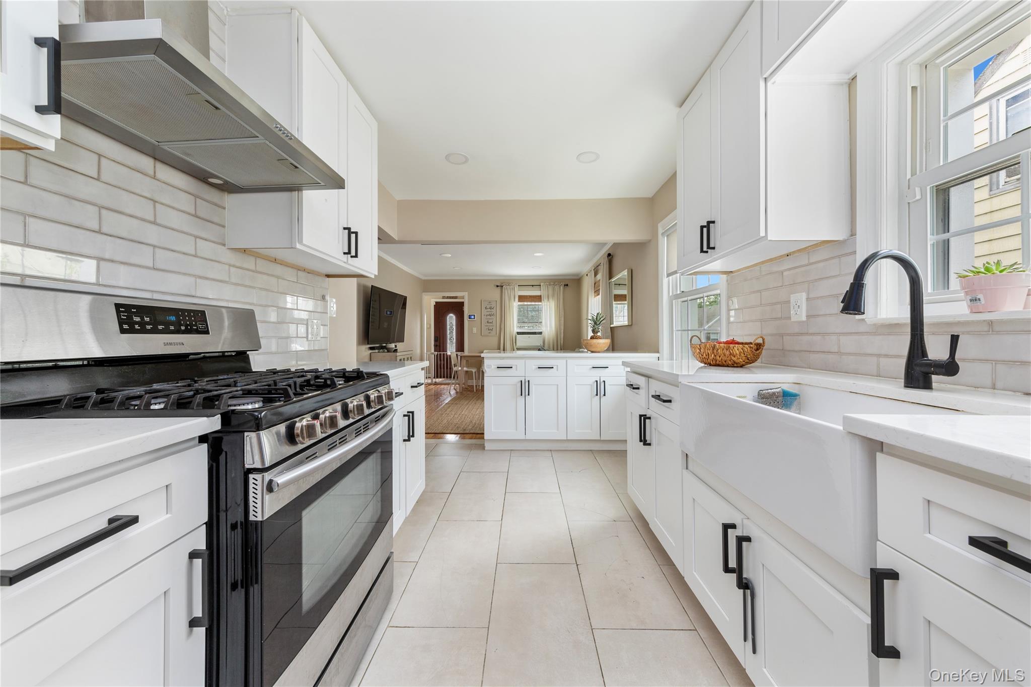 11 Dewitt Street Valley Stream, NY 11580 - Photo 8 of 21 Kitchen with tasteful backsplash, stainless steel gas stove, white cabinets, wall chimney range hood, and light tile patterned floors