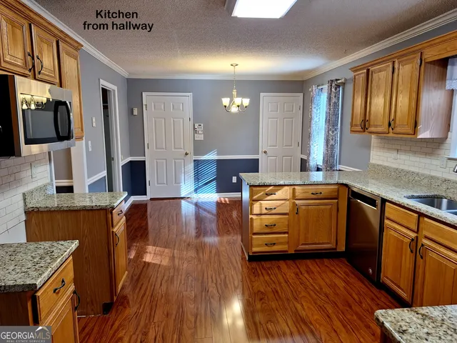 a kitchen with stainless steel appliances granite countertop wooden cabinets a sink and dishwasher with wooden floor