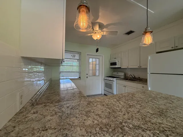 a kitchen with granite countertop a stove a sink and a refrigerator