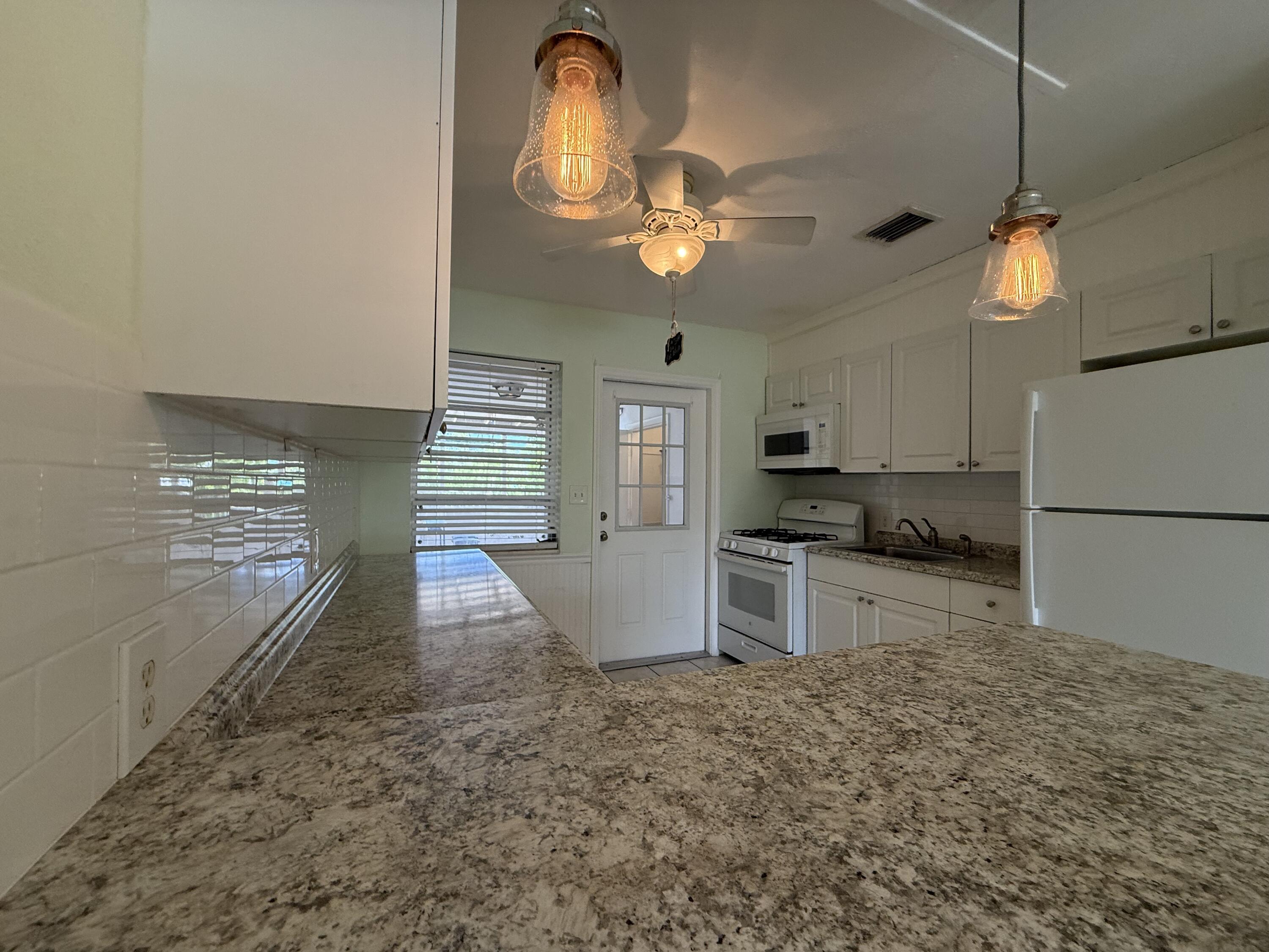 3962-3964 No Name Road Big Pine Key, FL 33043 - Photo 13 of 26 a kitchen with granite countertop a stove a sink and a refrigerator