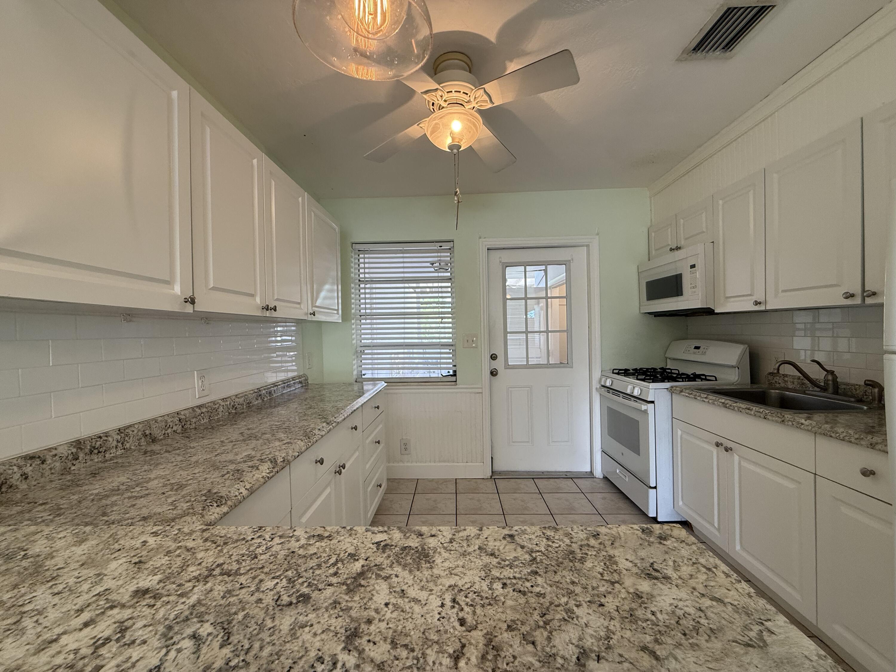 3962-3964 No Name Road Big Pine Key, FL 33043 - Photo 14 of 26 a kitchen with granite countertop a stove a sink and a refrigerator