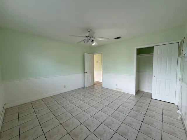 an empty room with windows and a ceiling fan