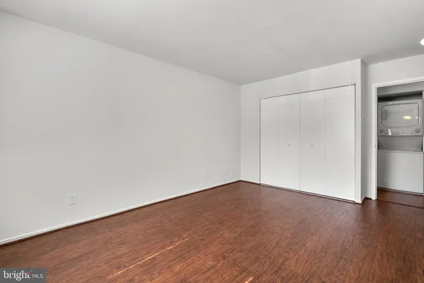 a view of an empty room with wooden floor and closet