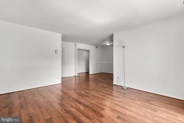 a view of an empty room with wooden floor and closet