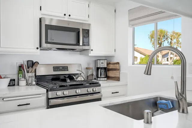 a kitchen with stainless steel appliances granite countertop a sink a stove and a microwave