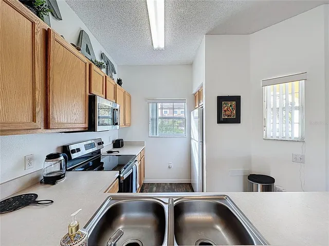 a kitchen with stainless steel appliances granite countertop a refrigerator a stove and a sink with wooden floors