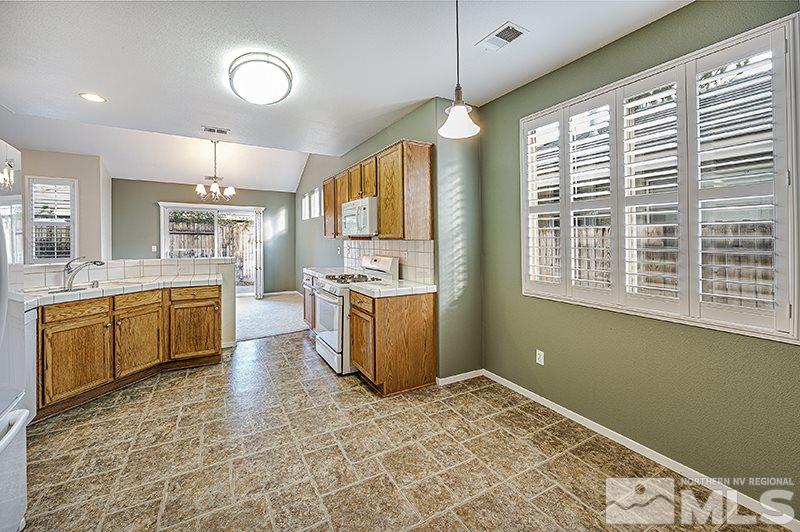1137 Tule Drive Reno, NV 89521 - Photo 7 of 17 a kitchen with stainless steel appliances kitchen island granite countertop a stove a sink dishwasher and a refrigerator