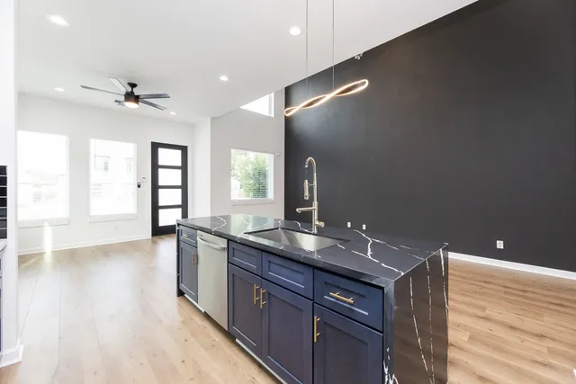a spacious bathroom with a granite countertop sink a light fixture and a wooden floor