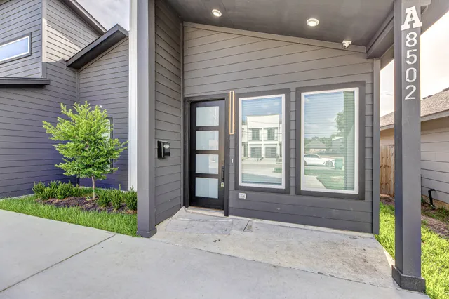 a front view of a house with a yard and potted plants
