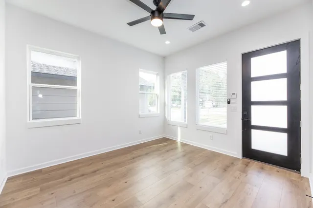 a view of an empty room with a window and wooden floor
