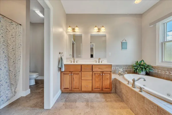 a spacious bathroom with a tub double sink and a large mirror