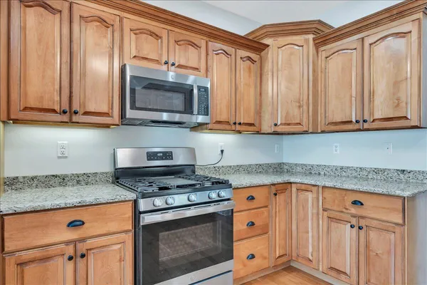 a kitchen with granite countertop a stove top oven microwave and cabinets