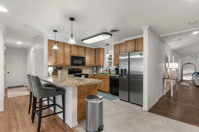 a kitchen with stainless steel appliances granite countertop a stove a refrigerator a oven a sink a dining table and chairs with wooden floor