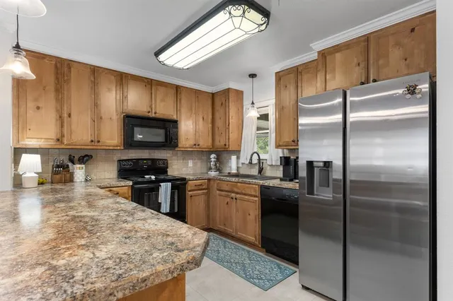 a kitchen with stainless steel appliances granite countertop a refrigerator a stove top oven a sink and dishwasher