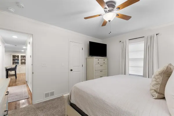 a bedroom with a bed and a flat tv screen on dresser