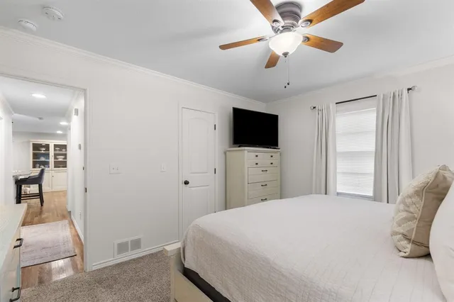 a bedroom with a bed and a flat tv screen on dresser