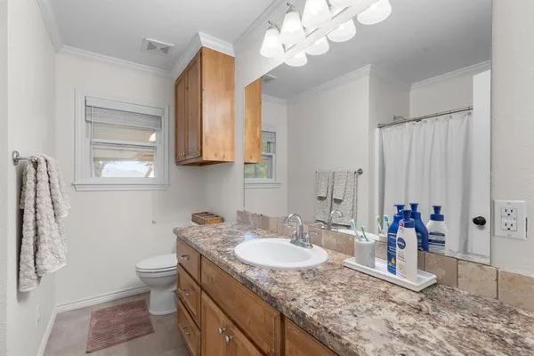 a bathroom with a granite countertop sink a toilet and a mirror