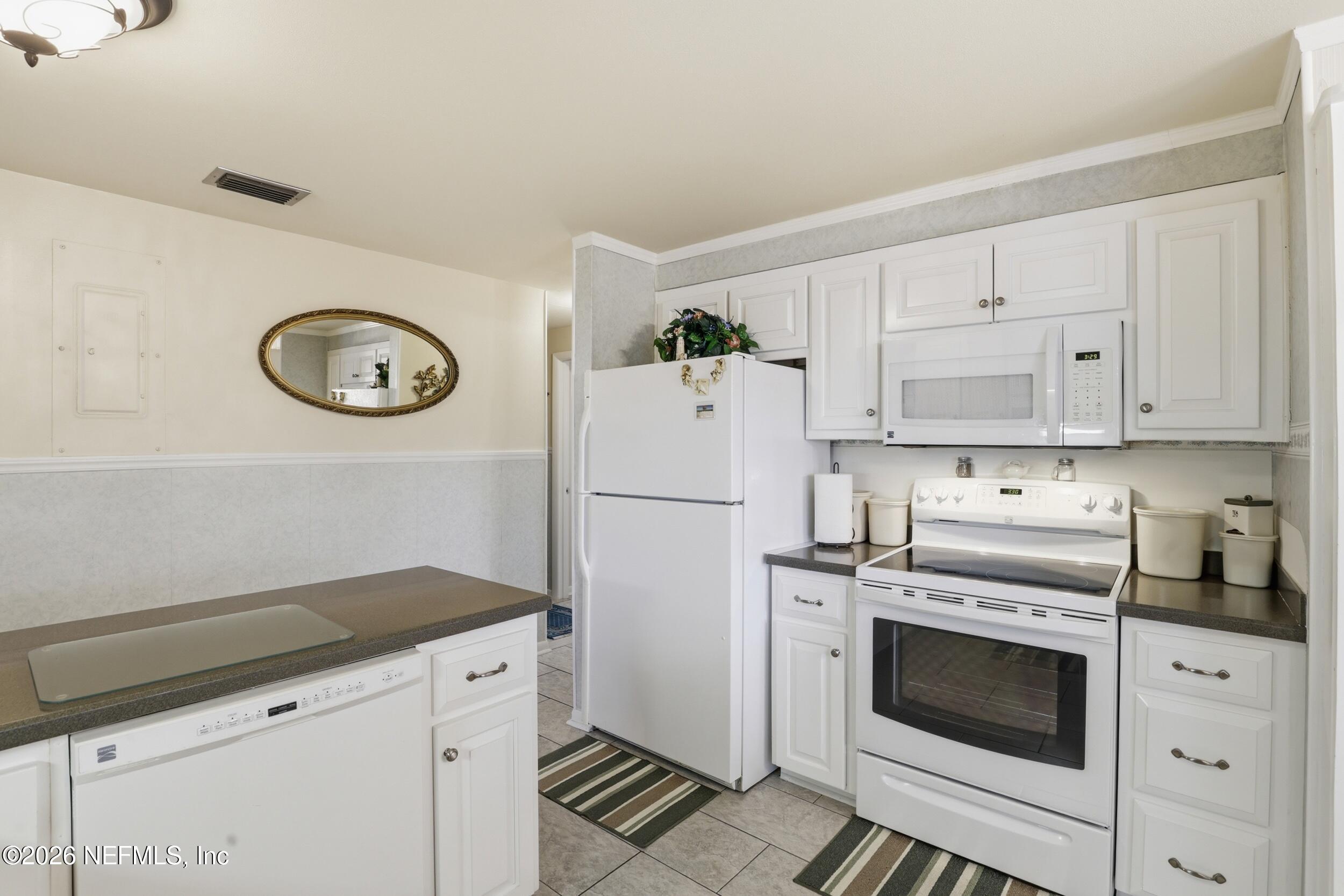 295 Northwest Berea Avenue Keystone Heights, FL 32656 - Photo 14 of 49 a kitchen with white cabinets and white appliances