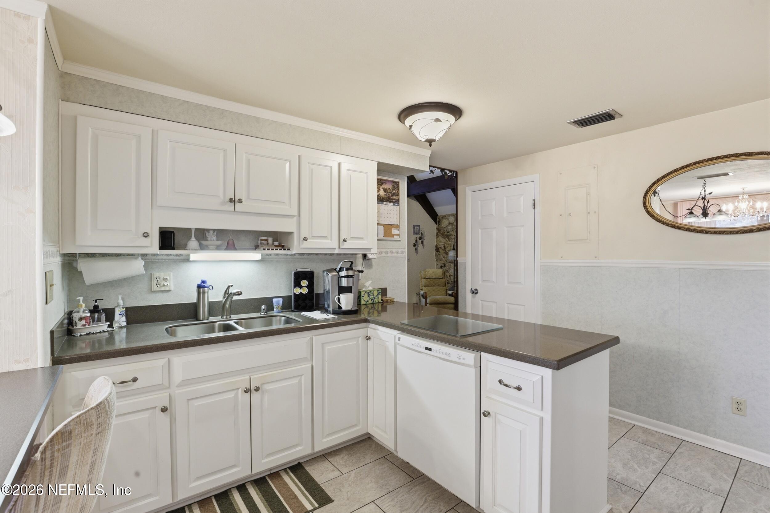 295 Northwest Berea Avenue Keystone Heights, FL 32656 - Photo 16 of 49 a kitchen with a sink dishwasher and white cabinets with wooden floor