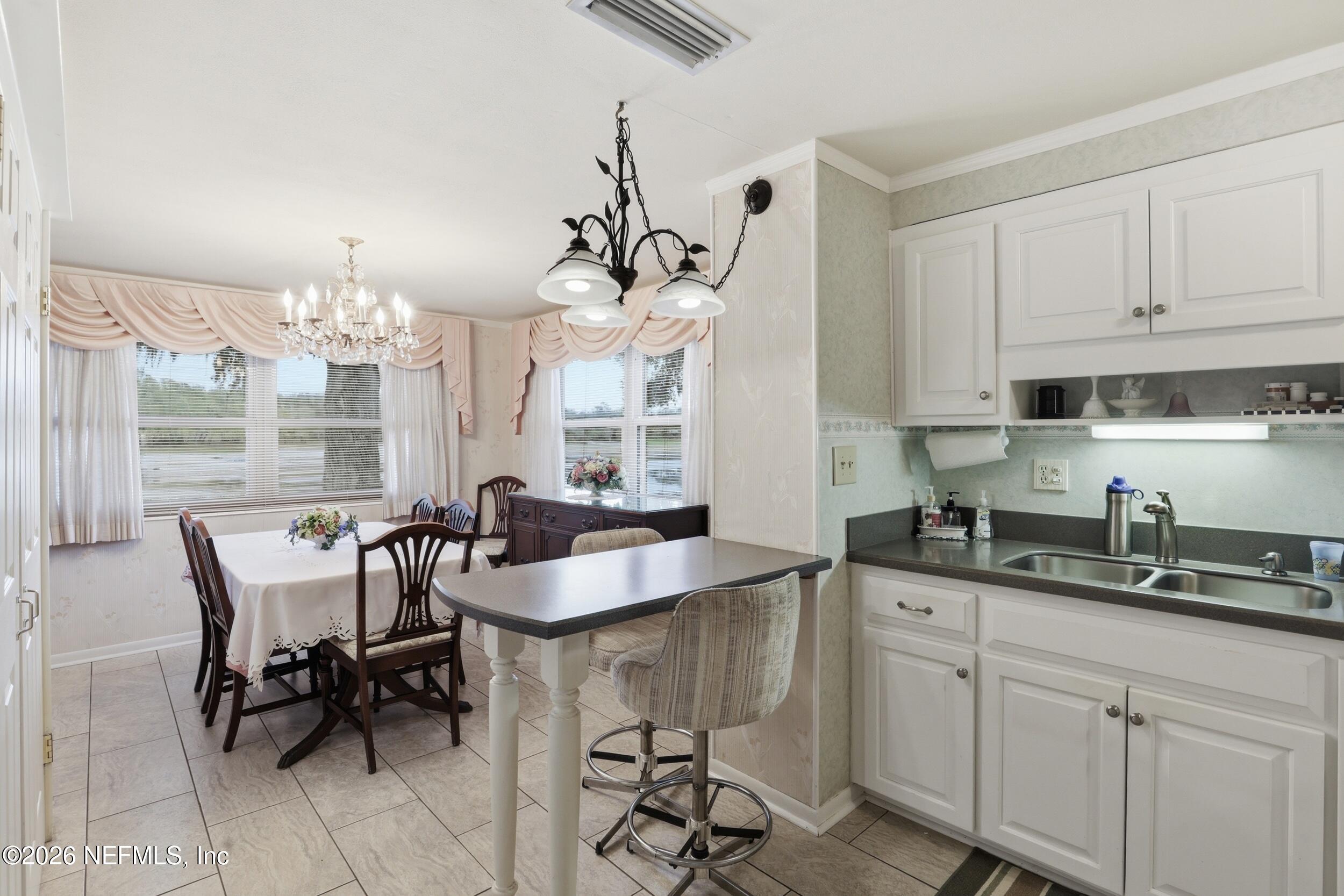 295 Northwest Berea Avenue Keystone Heights, FL 32656 - Photo 10 of 49 a kitchen with kitchen island granite countertop a sink a center island a dining table and chairs