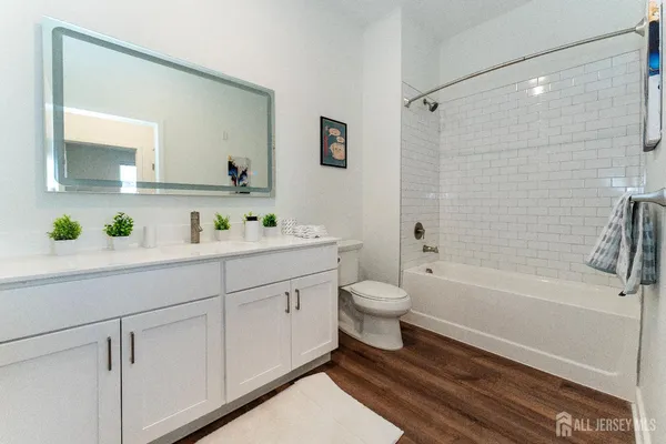 a bathroom with a bathtub shower sink vanity and toilet