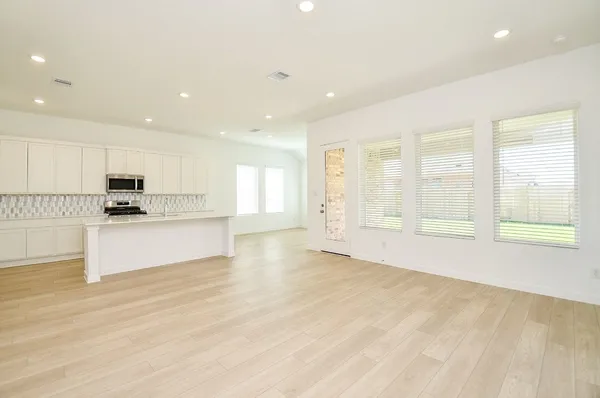 a large kitchen with stainless steel appliances granite countertop a stove a sink white cabinets and a large window