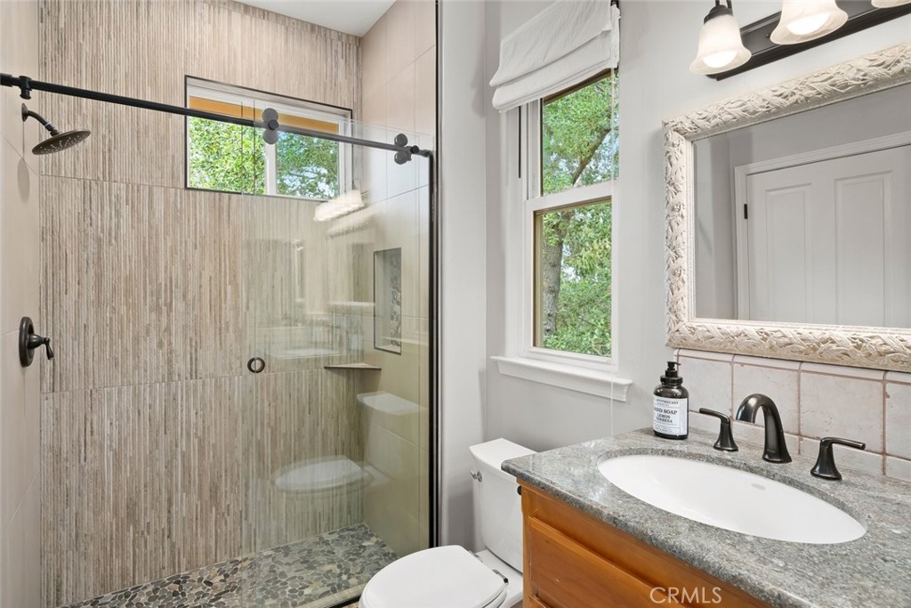 5982 Violeta Avenue Atascadero, CA 93422 - Photo 59 of 75 a bathroom with a granite countertop sink toilet a mirror and shower