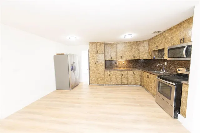 a large kitchen with kitchen island granite countertop a refrigerator and cabinets