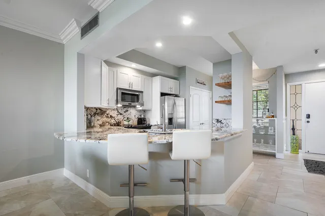 a kitchen with a dining table chairs cabinets and stainless steel appliances