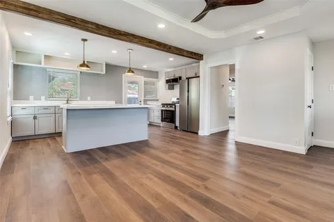 a large kitchen with stainless steel appliances granite countertop a refrigerator a stove and a wooden floors