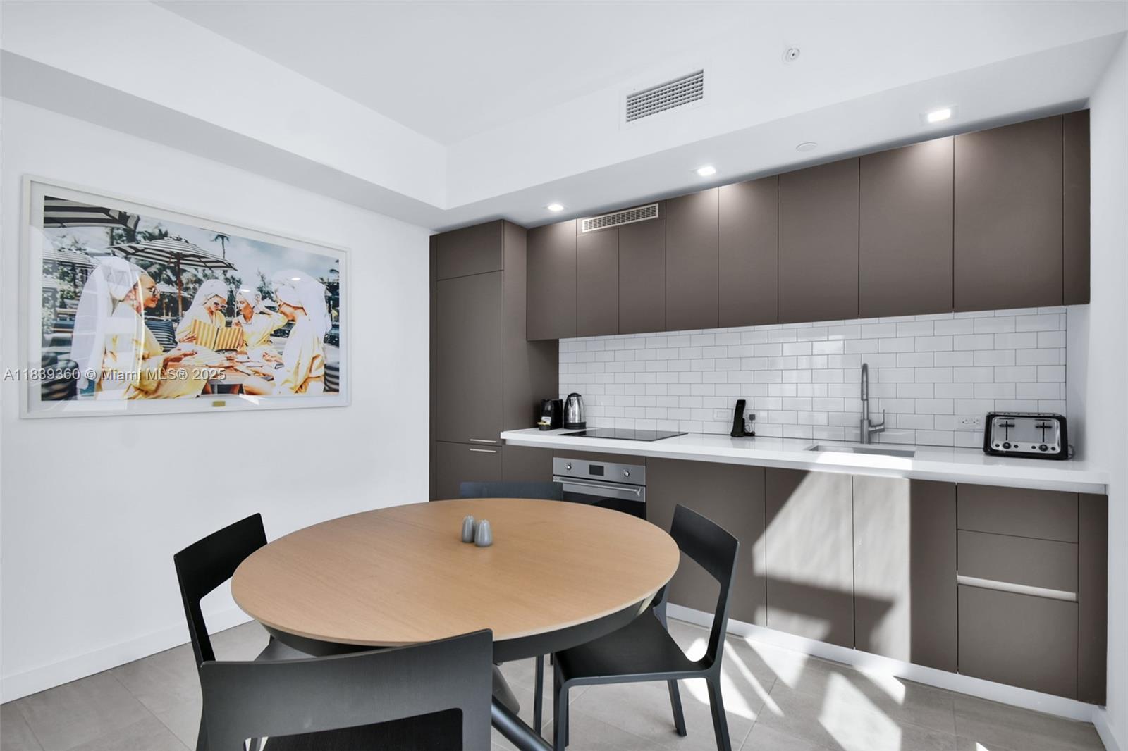 227 Northeast 2nd Street, Unit 2000 Miami, FL 33132 - Photo 11 of 44 a kitchen with a table chairs sink and cabinets