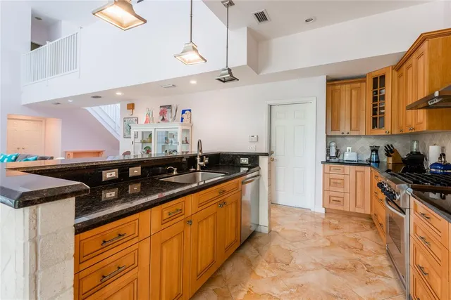 a kitchen with granite countertop a sink stainless steel appliances and cabinets
