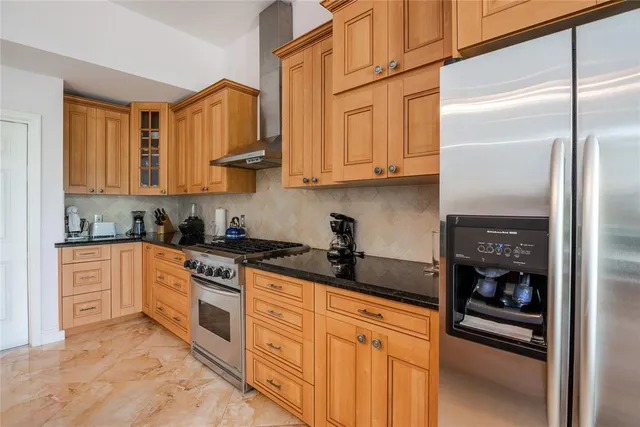 a kitchen with stainless steel appliances granite countertop a refrigerator a stove and a sink