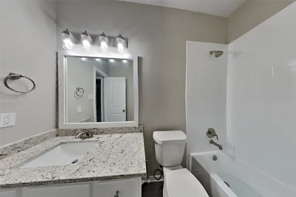 a bathroom with a granite countertop sink a toilet and shower