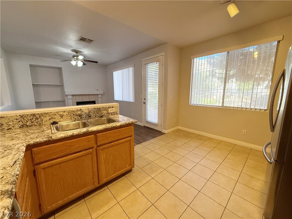 2185 Polynesia Circle Henderson, NV 89074 - Photo 13 of 37 An inviting kitchen with tile floors and ample natural light, flowing into a living space with a fireplace and built-in shelving.