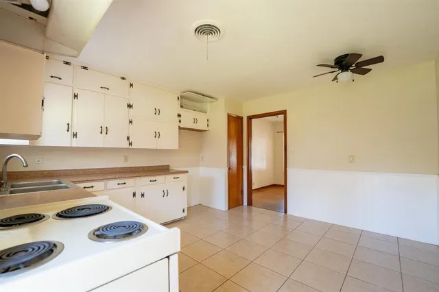 a kitchen with a stove a refrigerator and white cabinets