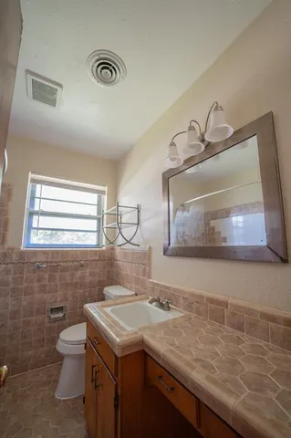 a bathroom with a granite countertop sink a toilet and a mirror