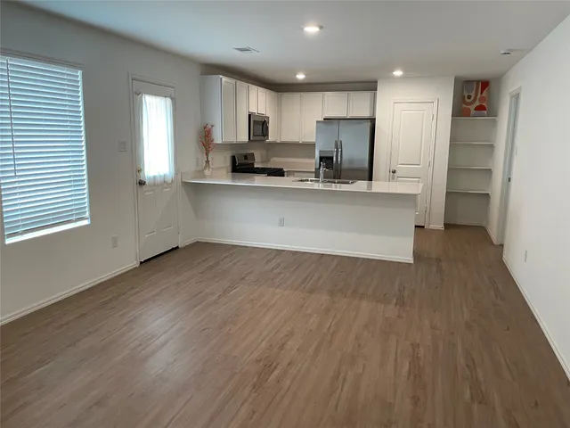 a kitchen with stainless steel appliances granite countertop a refrigerator a sink dishwasher a stove and white countertops with wooden floor