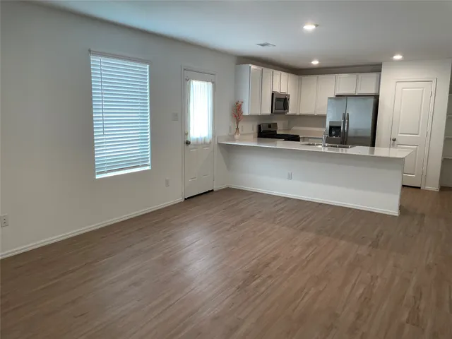 a view of kitchen with granite countertop stainless steel appliances sink refrigerator and window