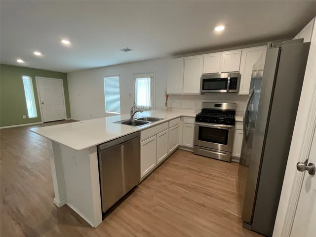 a kitchen with stainless steel appliances a stove a sink a refrigerator a window