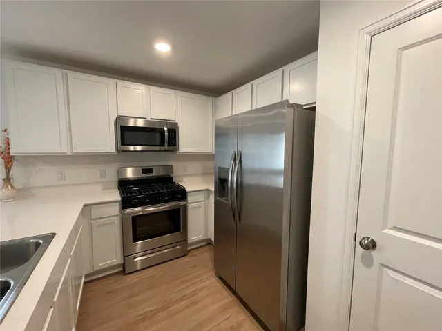 a kitchen with stainless steel appliances granite countertop a refrigerator a stove a sink and a microwave