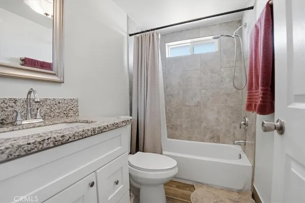 a bathroom with a granite countertop sink a toilet and shower