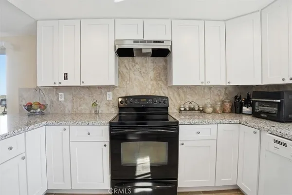 a kitchen with granite countertop white cabinets and stainless steel appliances