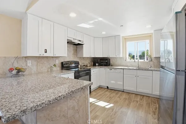 a kitchen with granite countertop white cabinets and white appliances