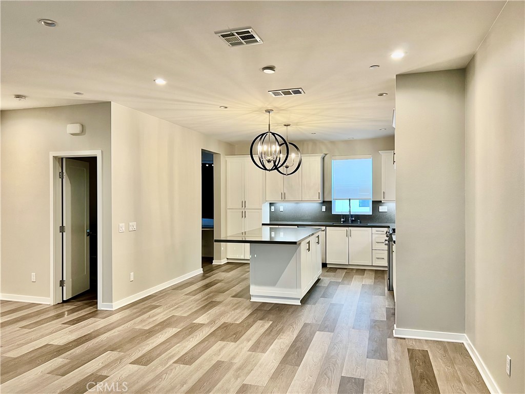 2336 Synergy Irvine, CA 92614 - Photo 7 of 24 a large white kitchen with a sink and dishwasher a stove with wooden floor